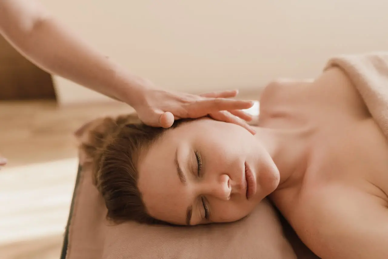 Therapist gently resting hands on a client’s ear in a peaceful treatment room during hopi ear candling